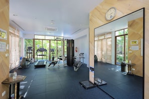 Ein Fitnessstudio mit Trainingsgeräten, großen Fenstern und einem Spiegel.