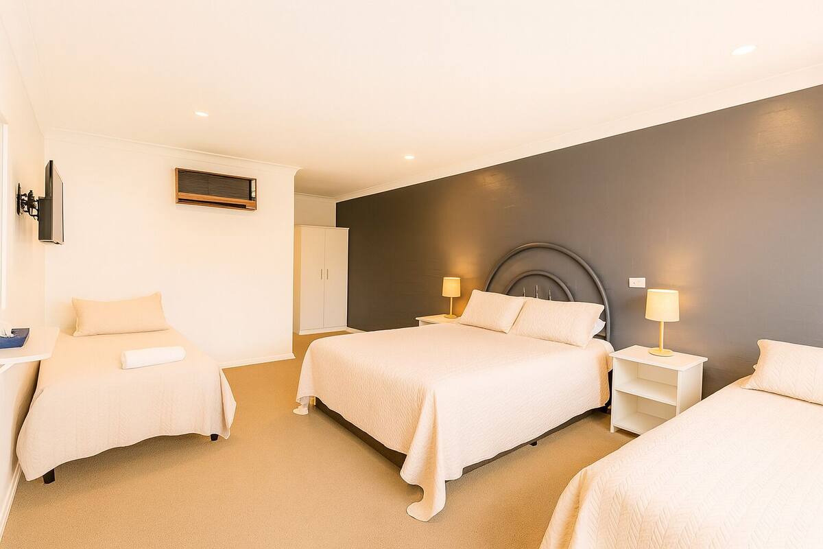 Quarto de hotel com duas camas, uma escrivaninha e um guarda-roupa.