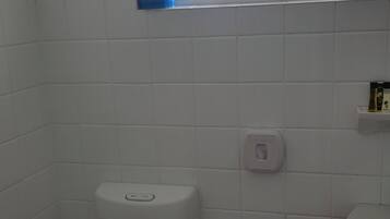 A small bathroom with a toilet, a window, and a sink.