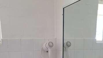 A bathroom with a white sink, a mirror, a hairdryer, and a towel rack.