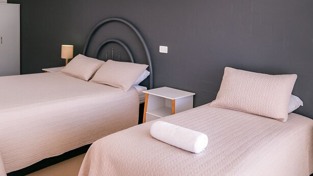 Une chambre d’hôtel avec deux lits, chacun doté d’une tête de lit et d’une table de chevet.