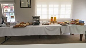 Un buffet de petit-déjeuner proposant une variété d’aliments et de boissons, ainsi qu’une machine à café et un réfrigérateur.