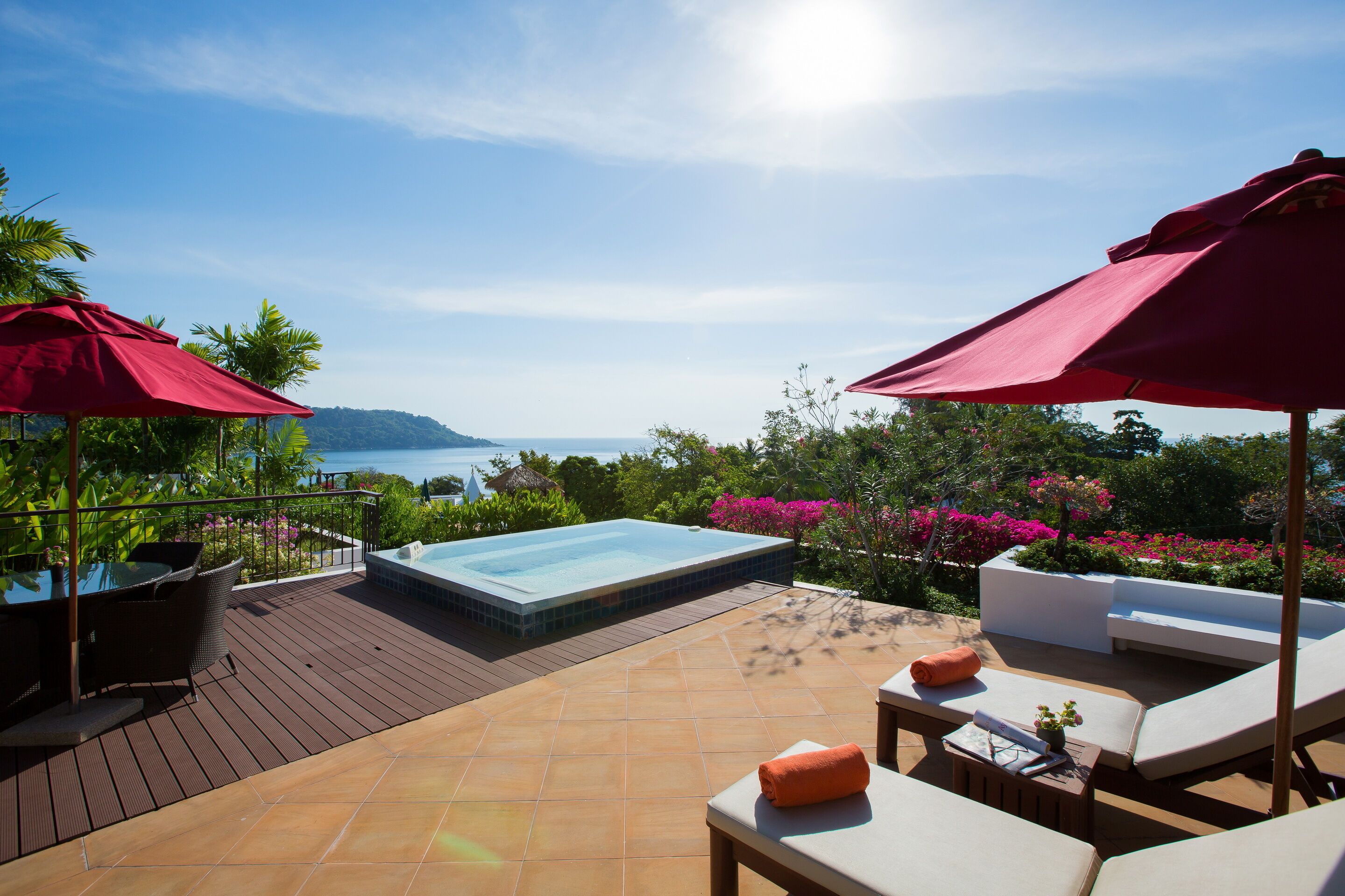 Terraza en la azotea con jacuzzi, sillas de descanso y sombrillas, con vistas panorámicas.
