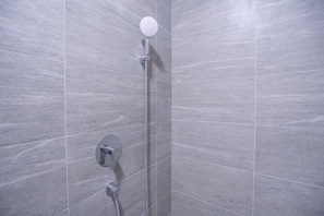 Een douche met een handdouche en een bedieningskraan aan de muur.