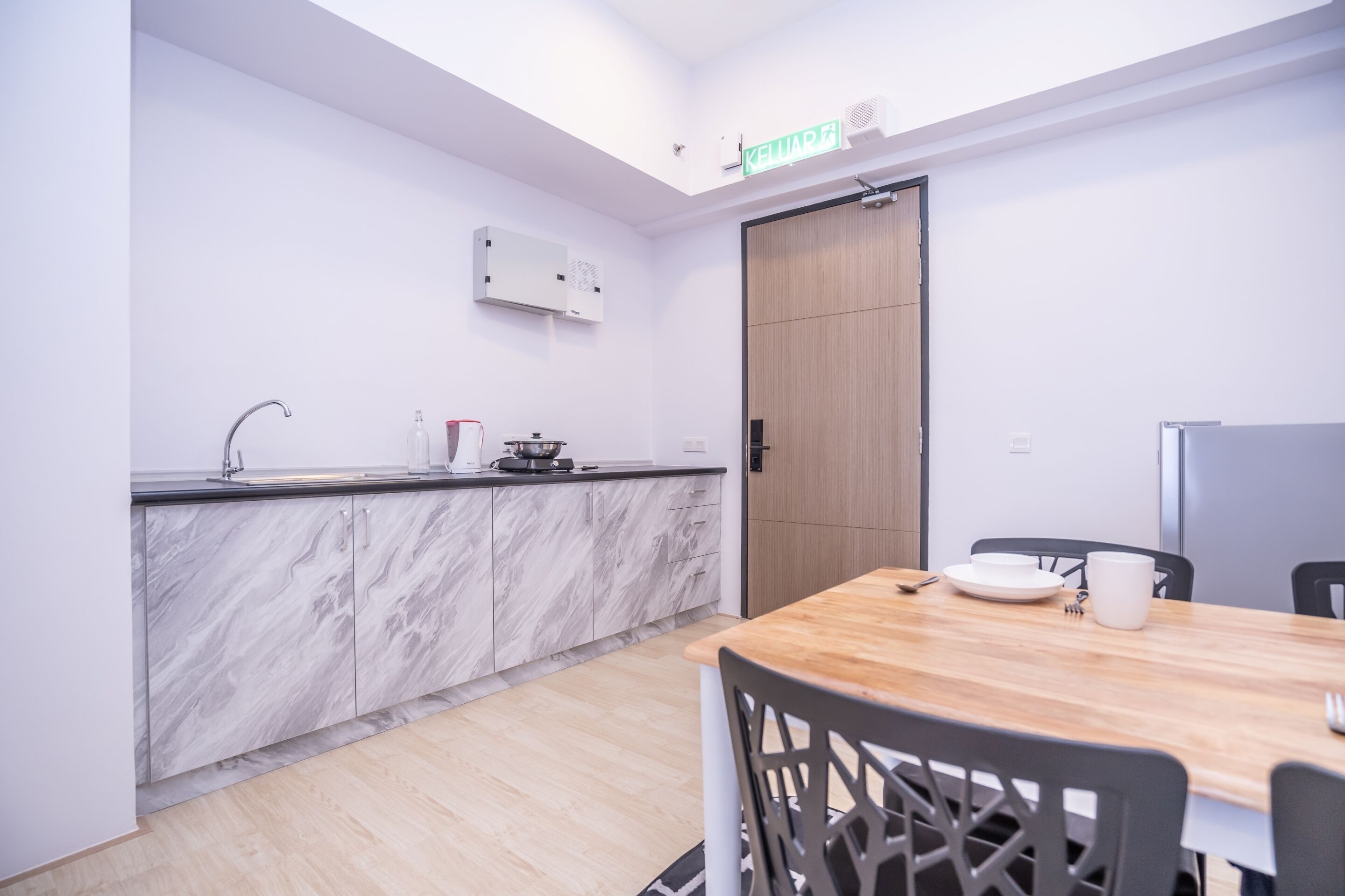 Una cocina moderna con armarios de mármol, una mesa de comedor de madera y un refrigerador blanco.
