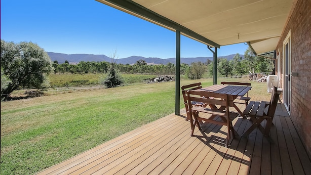Un espacio al aire libre cubierto con una terraza de madera, una mesa y sillas.