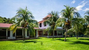 A house with a red roof, surrounded by lush green grass and palm trees. - Hotel O Terap Inn Kuala Nerang (Kuala Nerang)