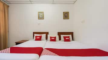A hotel room with two beds, each with white bedding and red accents, a wooden headboard, and a nightstand.