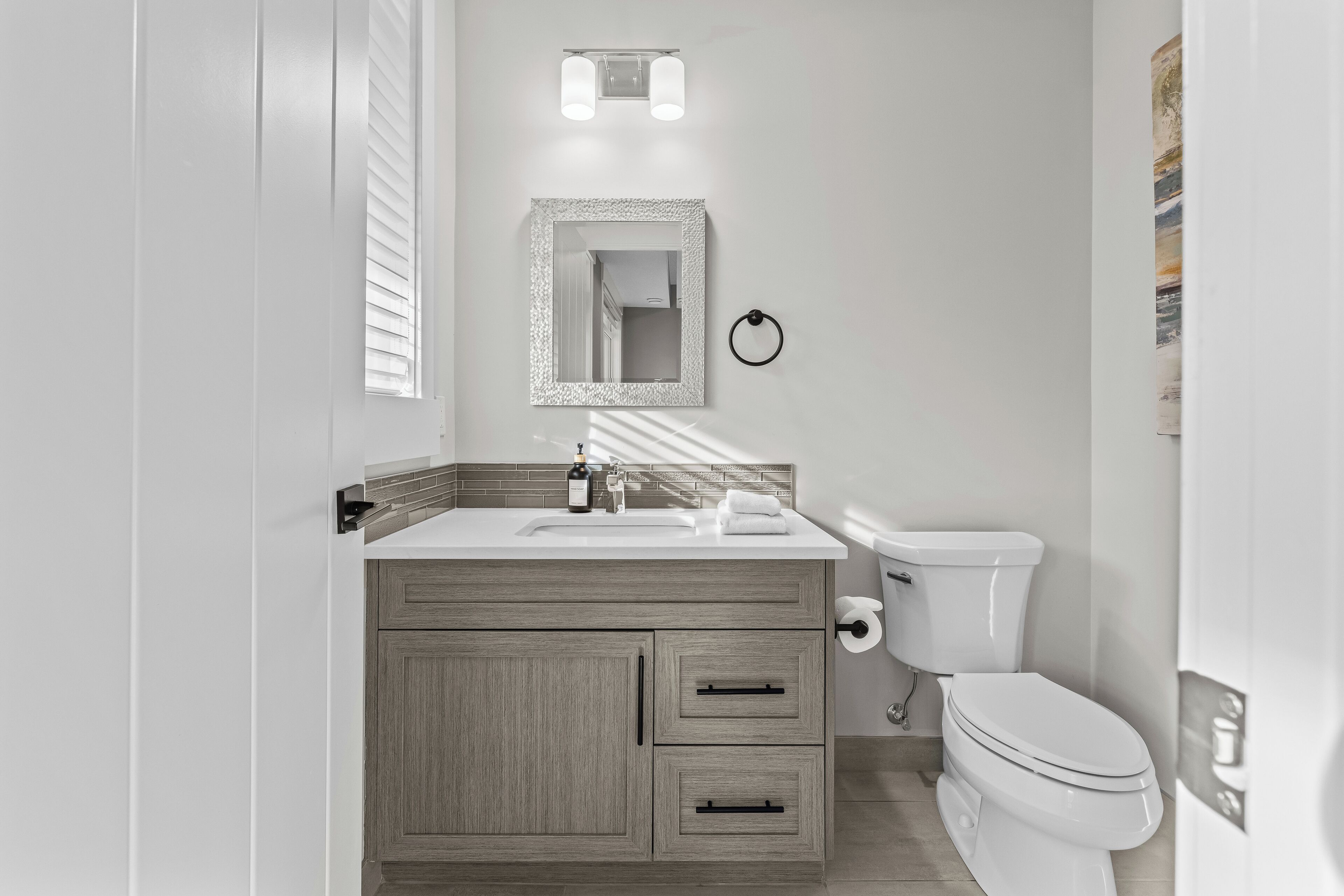 A modern bathroom with a white sink, vanity, and toilet.