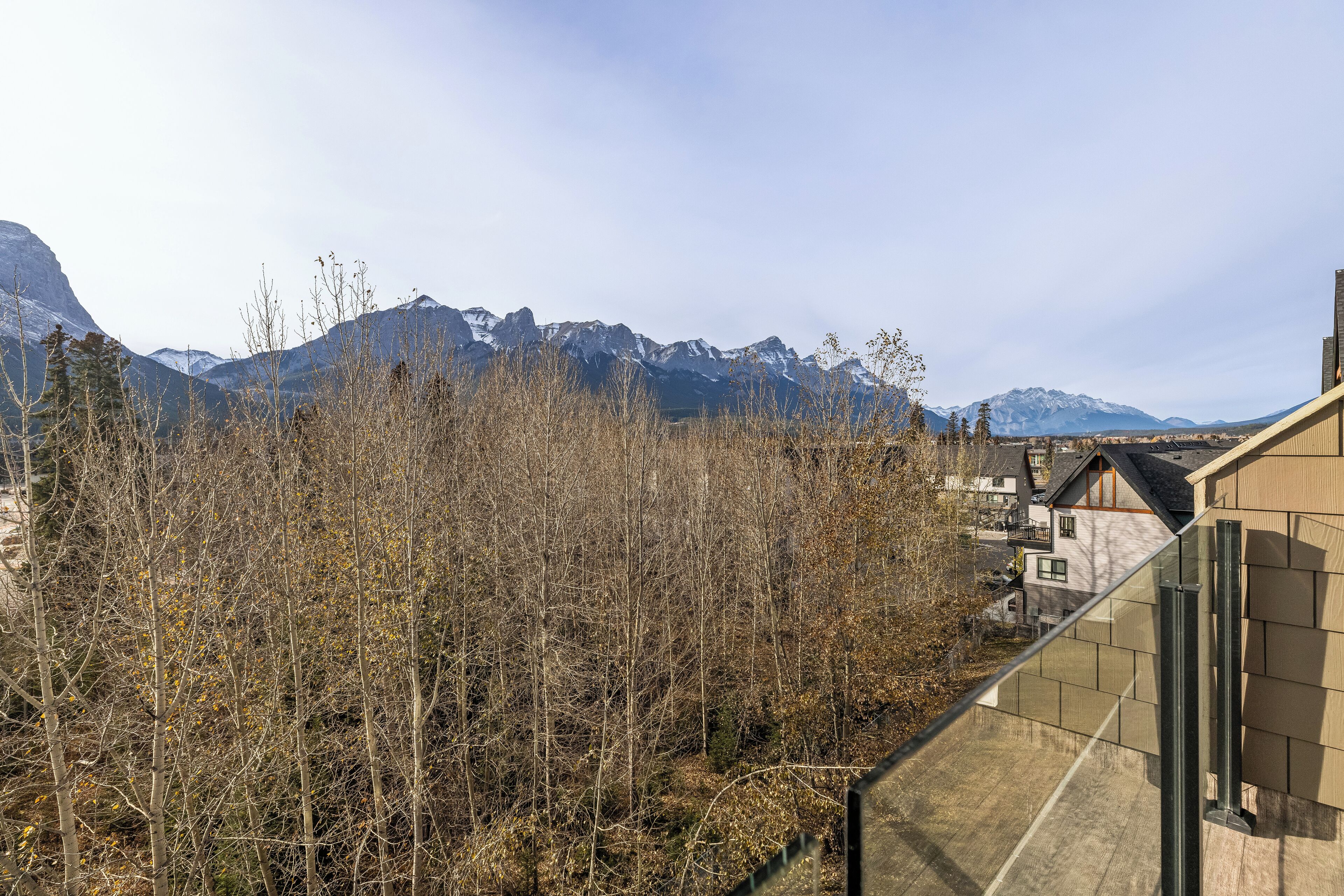A residential area with a mountain backdrop, featuring a modern house with a visible balcony and a clear view of the mountains.