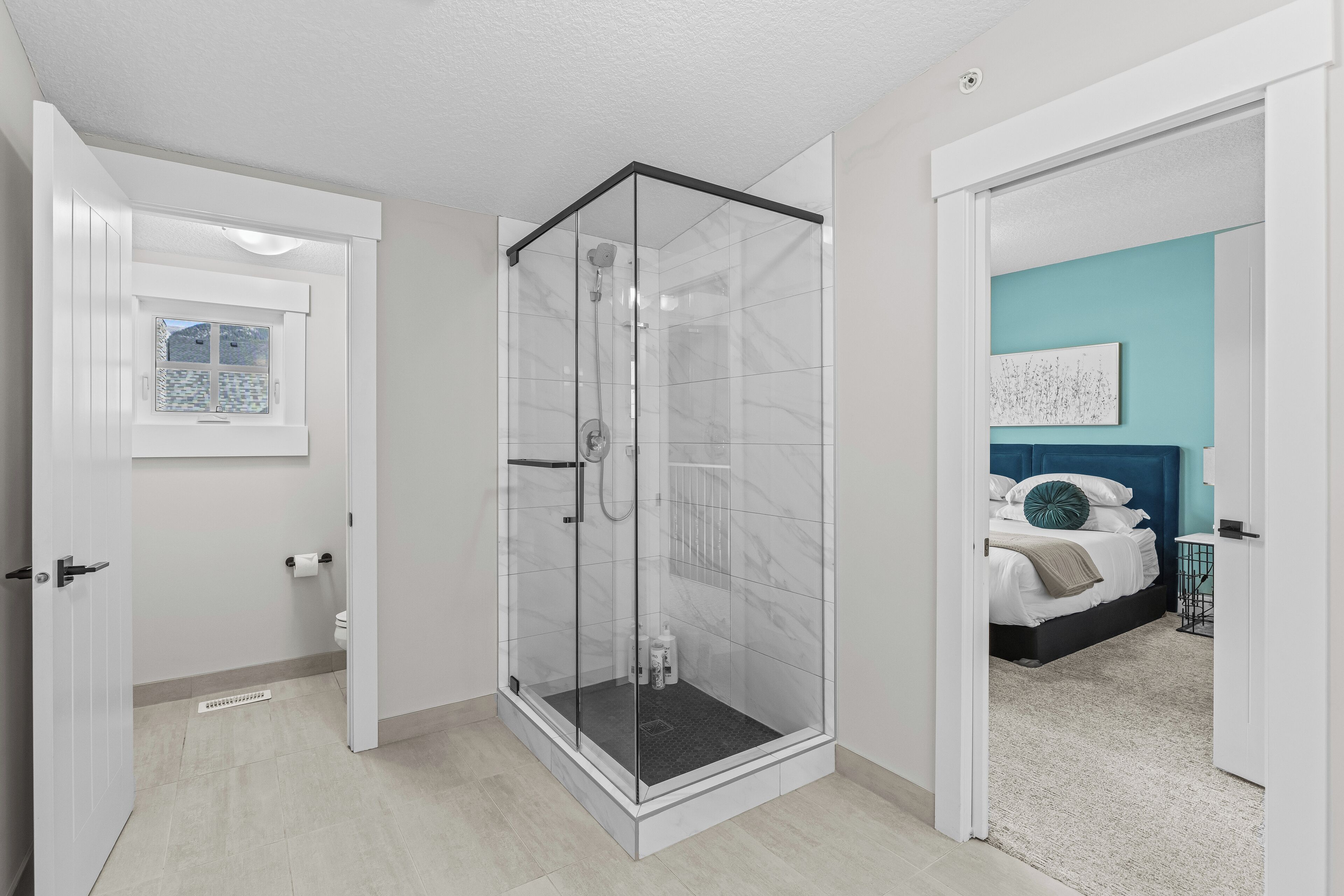 A modern bathroom with a glass shower enclosure, a toilet, and a window.