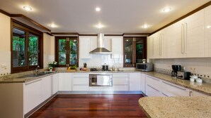 A modern kitchen with white cabinets, a stainless steel stove, and a microwave. - Katamanda Kata View villa E5 near kata Noi Beach (Karon)