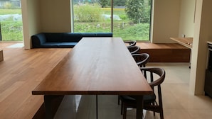 Un comedor moderno con una larga mesa de madera, sillas negras y un sofá azul.