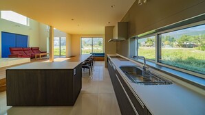 Una cocina moderna con una isla grande, un comedor y vistas a un paisaje verde.