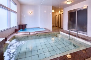 A hot tub with a tiled floor, a wooden bench, and a glass door leading to a shower area. - ANA Crowne Plaza Resort Okinawa Uruma Hills by IHG (Uruma)