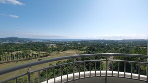 A balcony with a metal railing overlooking a green landscape with trees and a distant view of a cityscape. - ANA Crowne Plaza Resort Okinawa Uruma Hills by IHG (Uruma)
