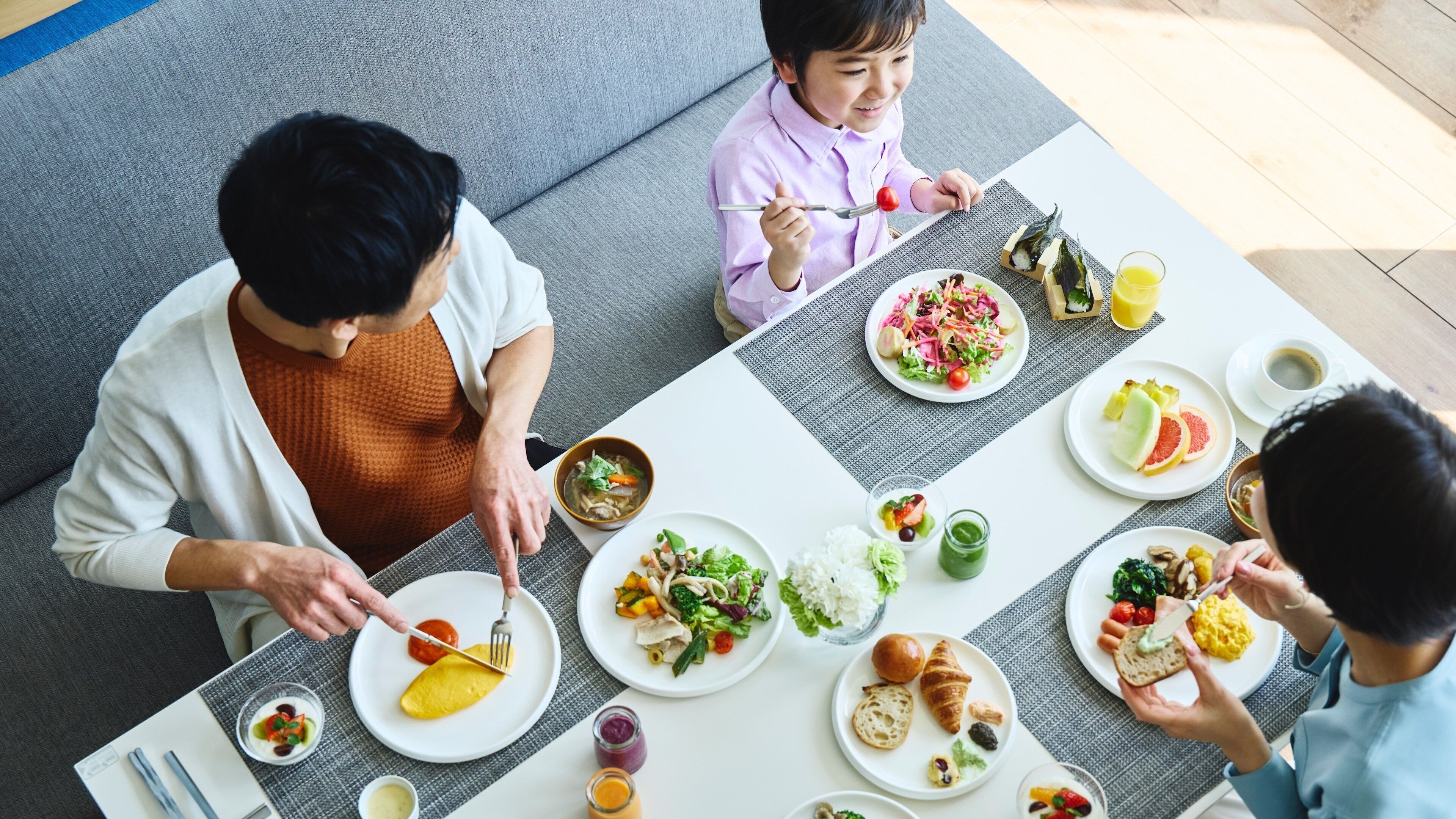 A dining table with various dishes, including salads, fruits, and bread.