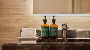 A bathroom with wooden paneling, two bottles of Antipodes hand and body lotion, a towel, and a marble countertop.