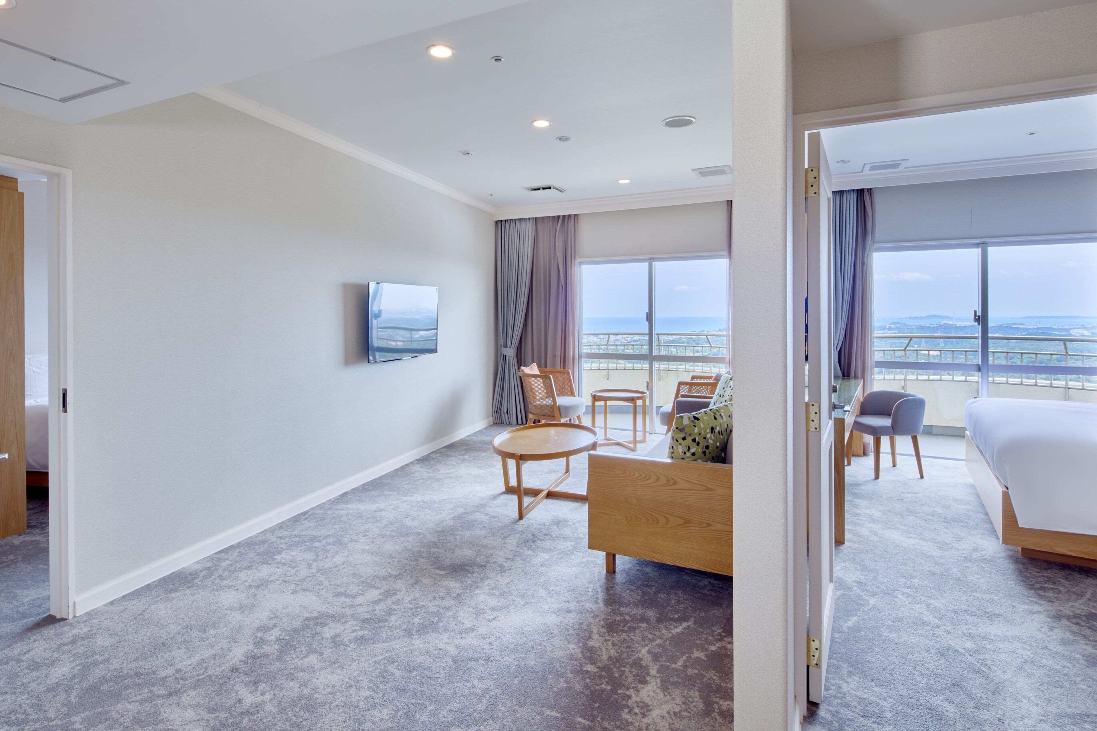 Une chambre d’hôtel comprenant un lit, une télévision, un balcon avec vue et un coin salon avec une table et des chaises.