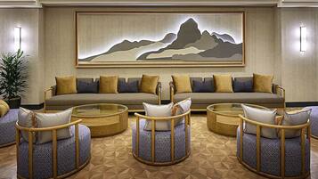 A modern living room with a sofa, two round coffee tables, and patterned ottomans.