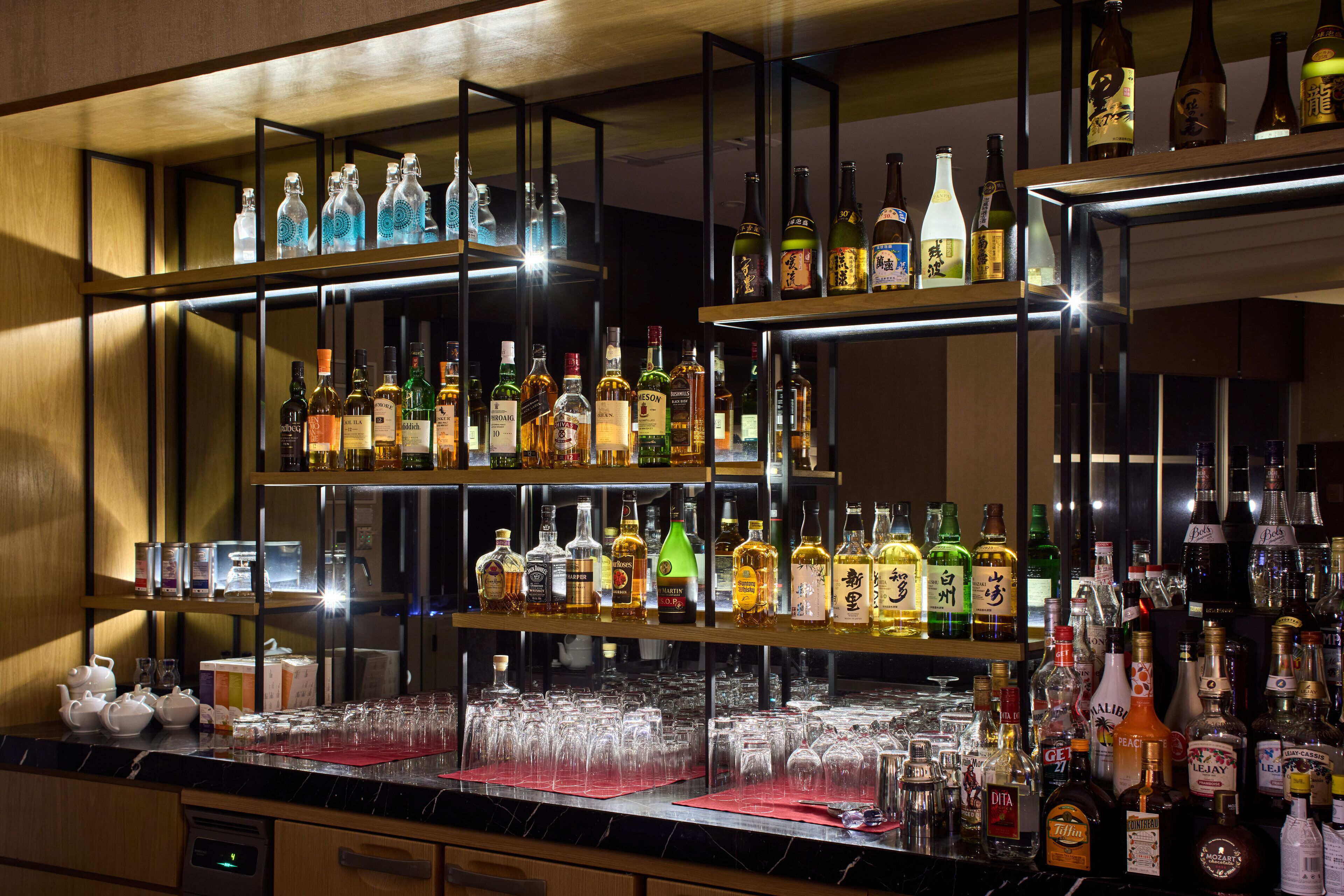 A bar area with multiple shelves of liquor bottles and glasses.