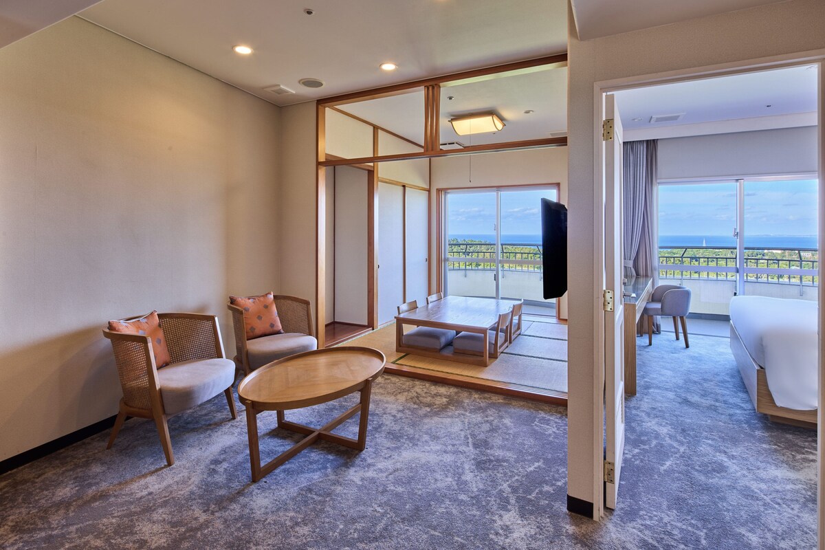 A hotel room with a balcony, a TV, and a seating area with a table and chairs.