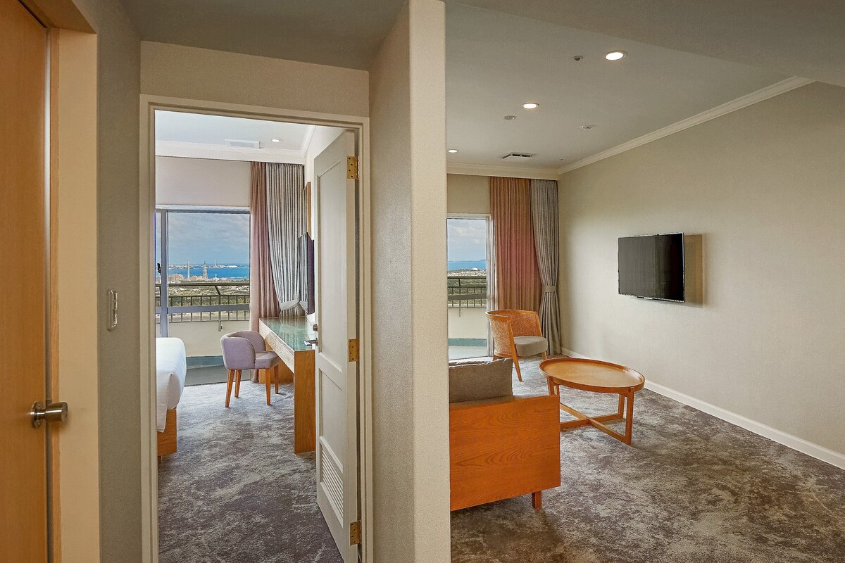 A hotel room with a balcony, a television, and a seating area.