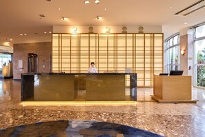 A reception area with a marble floor, a reception desk, and a wooden partition with clocks. - ANA Crowne Plaza Resort Okinawa Uruma Hills by IHG (Uruma)