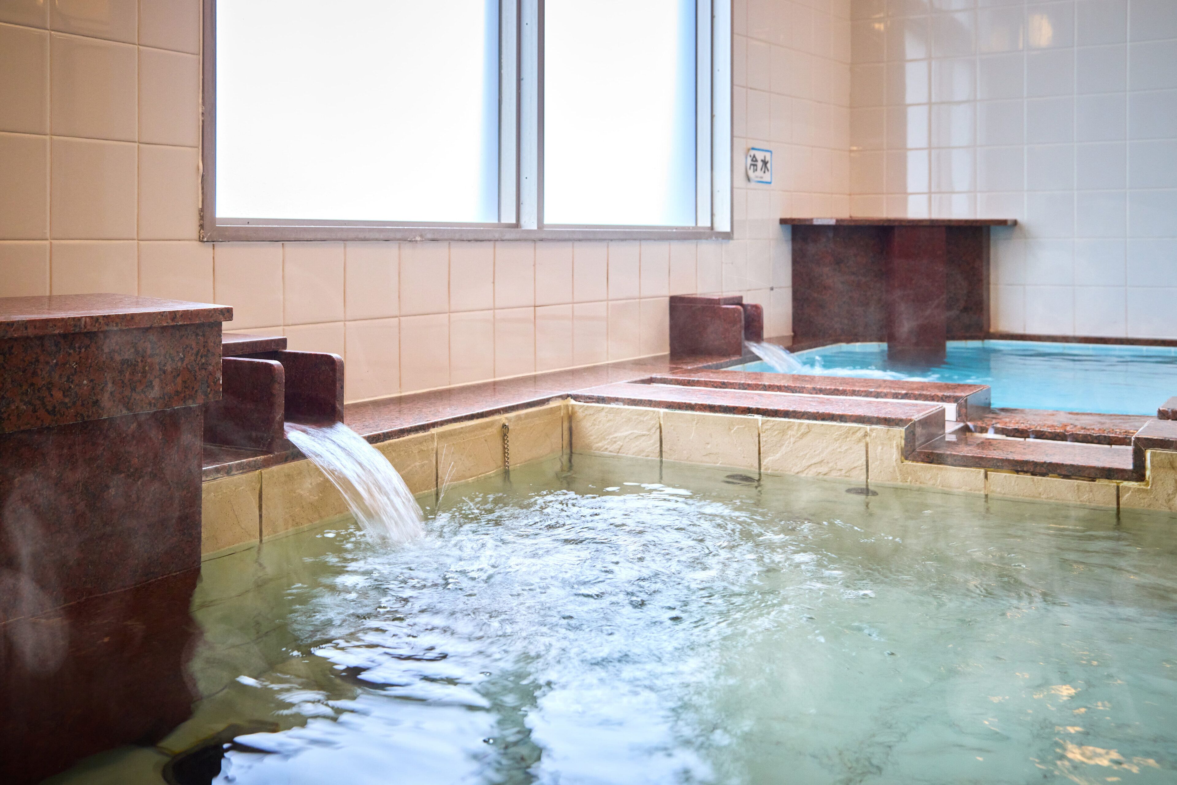 A hot tub area with a water feature and steps leading into the tub.