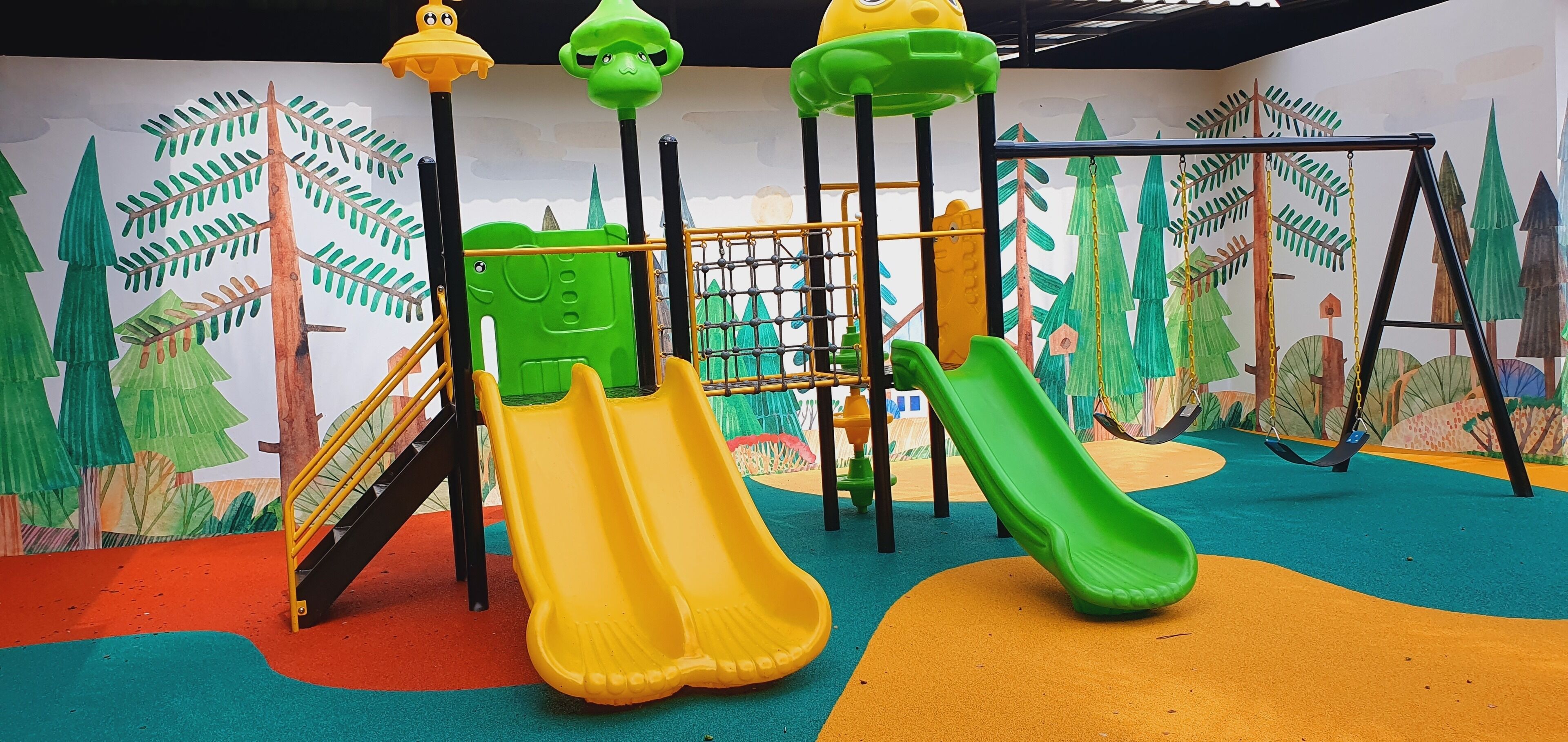 A children's play area with slides, climbing structures, and a colorful mural.