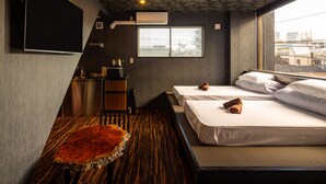 Habitación de hotel con una cama grande, un escritorio pequeño, una silla y una ventana con vistas a edificios.