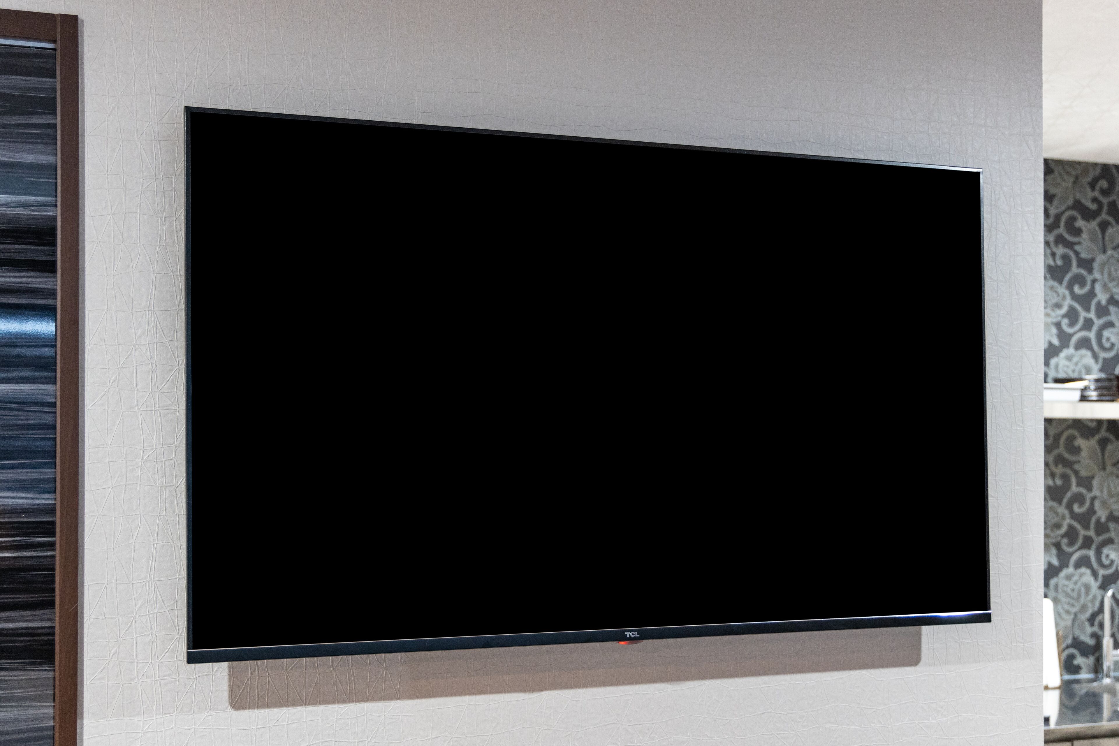 Un téléviseur à écran plat fixé à un mur dont la surface est texturée.