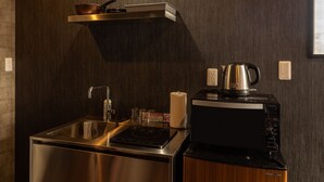 Una cocina compacta con un lavamanos de acero inoxidable, una estufa integrada y un refrigerador pequeño.