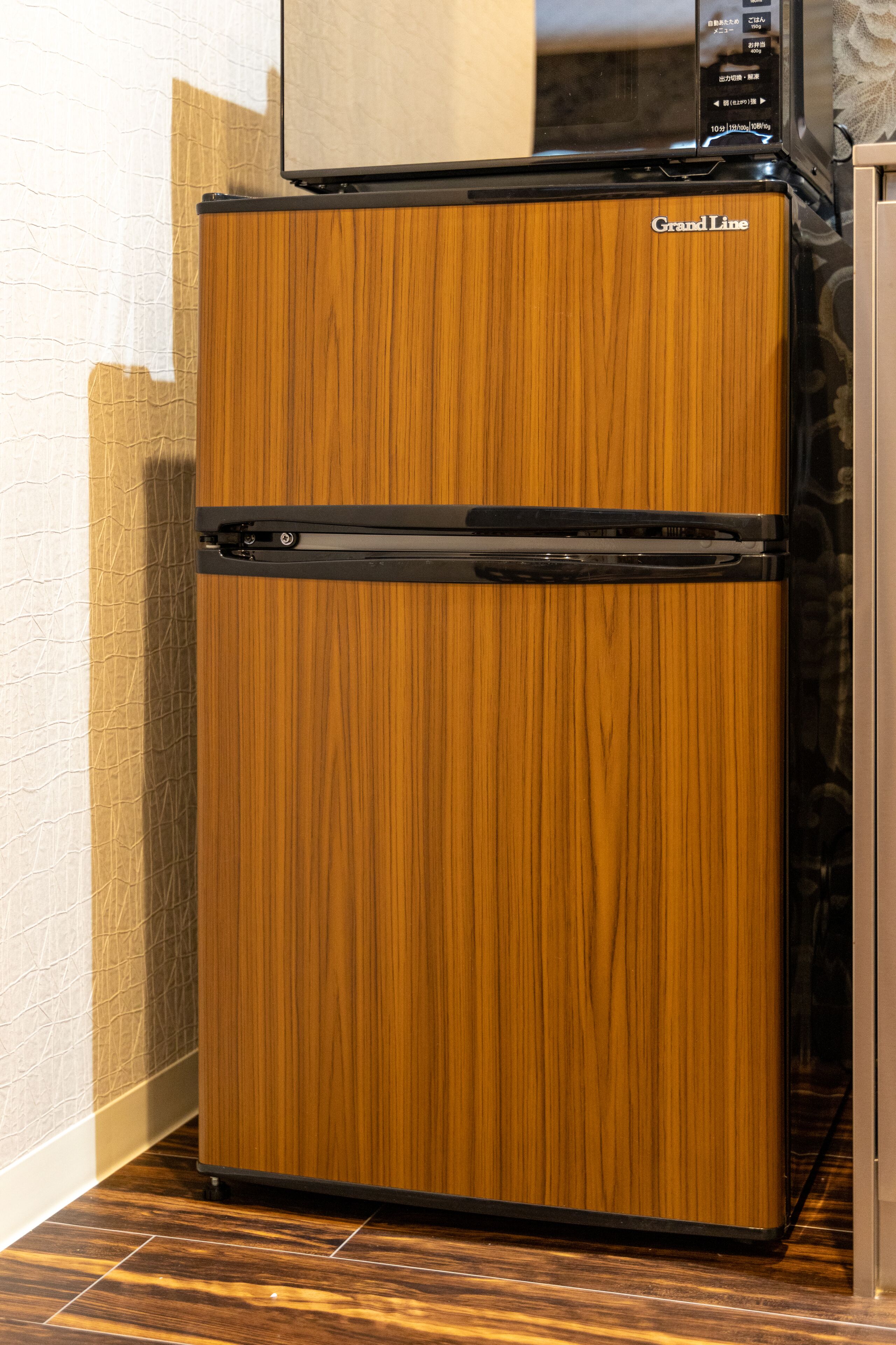Een compacte, houten koelkast met een schuifdeur, gelabeld 'Grand Line'.