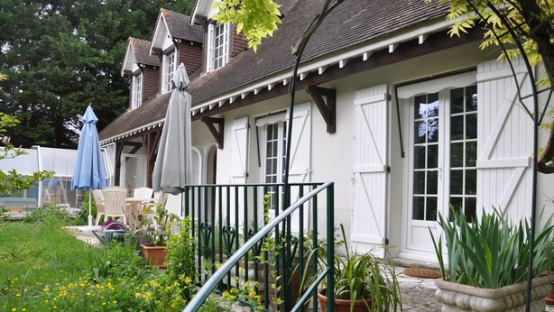 Ein weißes Gebäude mit einer Veranda, Pflanzkübeln und Gartenmöbeln.