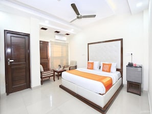 Une chambre d’hôtel avec un grand lit, un ventilateur de plafond, un bureau et un petit placard.