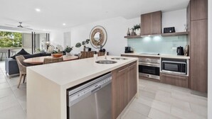 A modern kitchen with a central island, built-in appliances, and a dining area with a sofa and table.