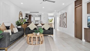 A modern living room with a grey sofa, a round wooden coffee table, and a ceiling fan.