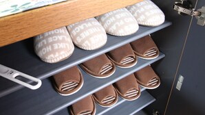 Un armadietto con scaffali che ospitano pantofole e un piccolo oggetto decorativo.