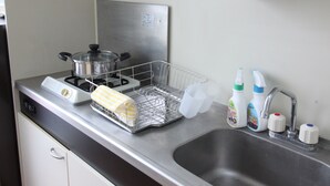 Una cucina con fornello, lavello e pensili. Sul piano di lavoro ci sono prodotti per la pulizia.