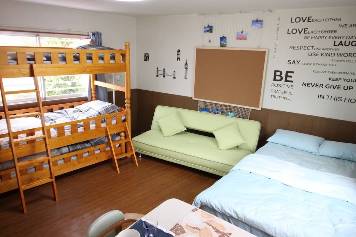 Una habitación con literas, un sofá y una cama. Hay carteles con mensajes motivadores en la pared.