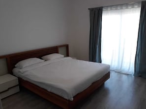 A neatly made bed with white linens in a room with a wooden headboard.
