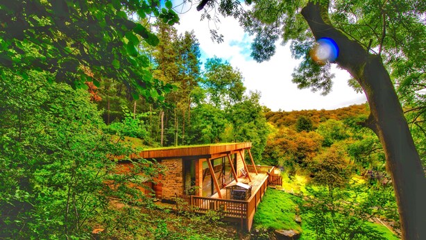 A wooden cabin with a deck, surrounded by dense forest. - A yorkshire dale that sleeps 6 guests  in 3 bedrooms (Richmond)