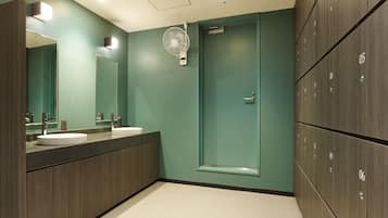 A modern bathroom with two sinks, a mirror, a fan, and a shower door.