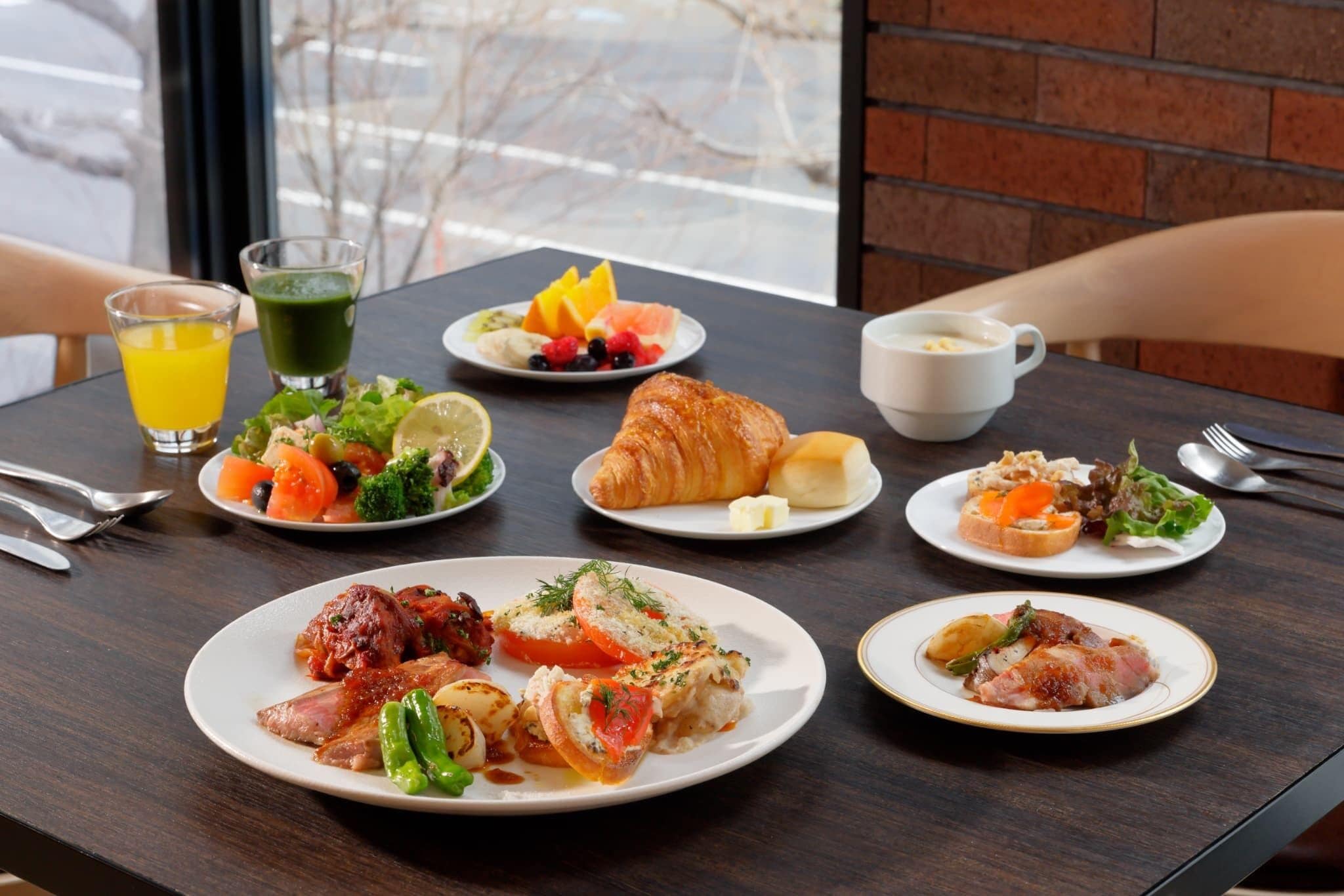A table with various breakfast items including croissants, fruit, and a green smoothie.