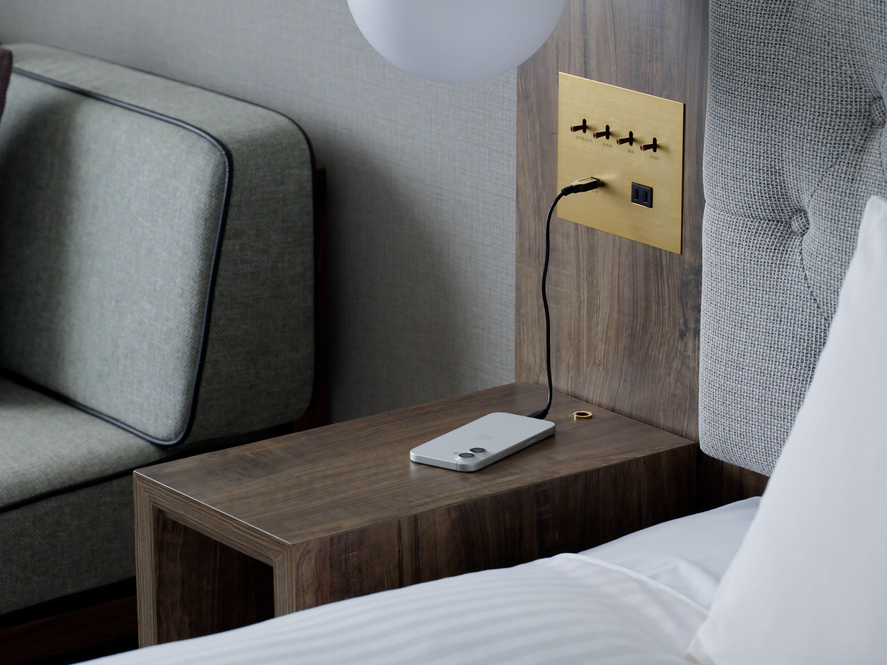 A hotel room with a wooden nightstand, a power outlet, and a laptop.