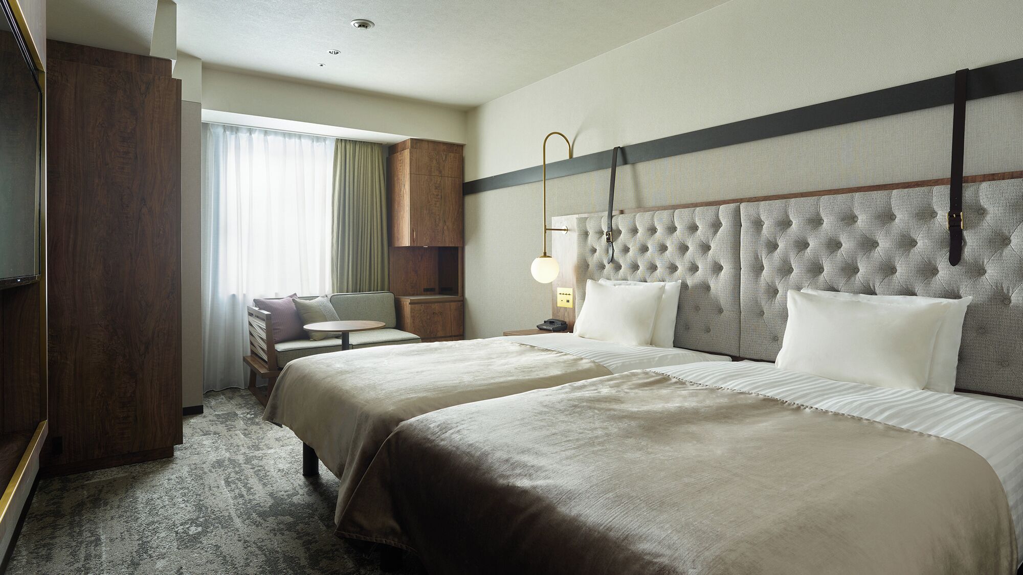 A hotel room with two beds, a sofa, a desk, and a television.