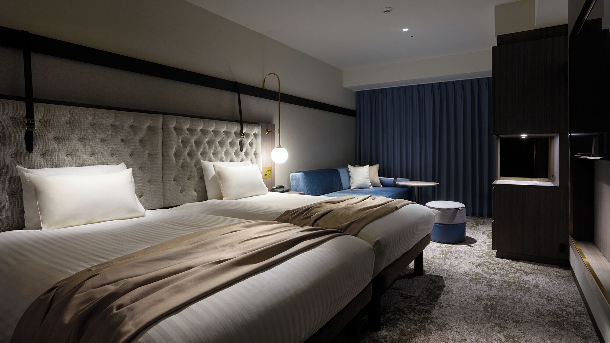 A hotel room with a large bed, a sofa, a small table, and a TV.