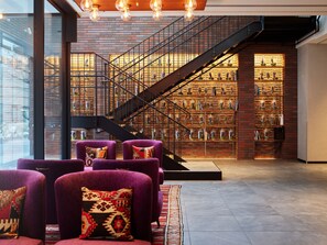 A modern interior with a staircase, purple armchairs, and a brick wall with shelves. - Mitsui Garden Hotel Sapporo West (Sapporo)