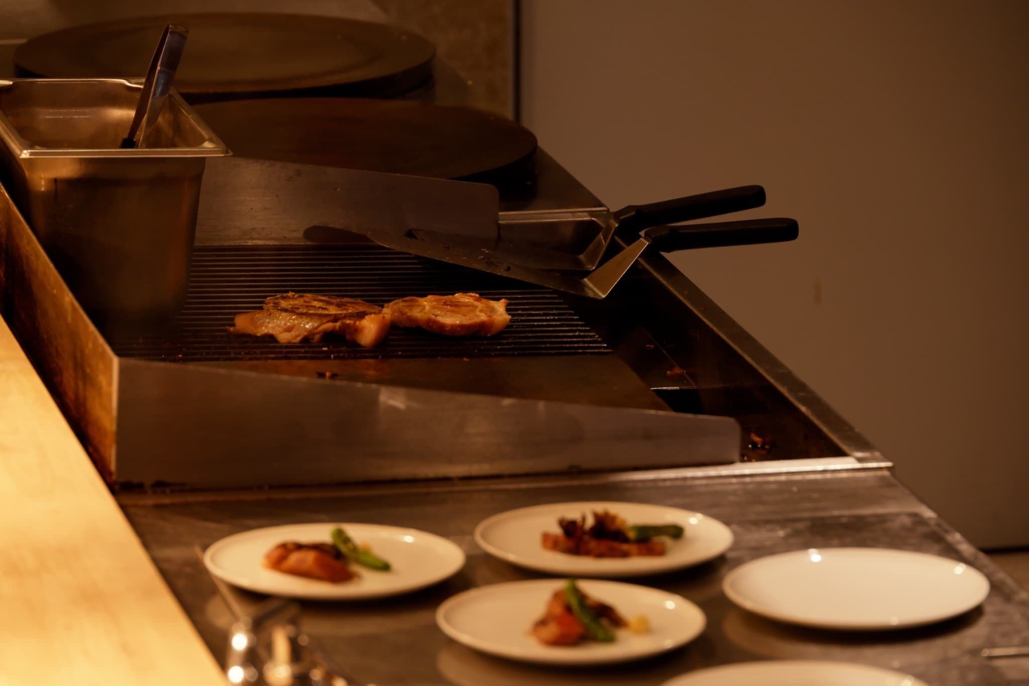 A kitchen with a grill, a pot, and plates with food.